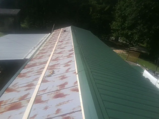 Old rusted panels beside newly installed green metal roofing — Wind Damage Roof Repair by Roofing Brothers in Genoa City