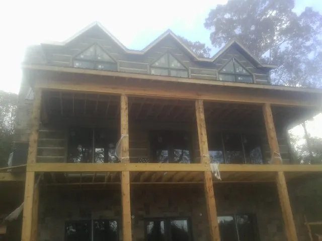 Dormers and porch framing on a large log home under construction — Roof Coating work by our crew in Genoa City