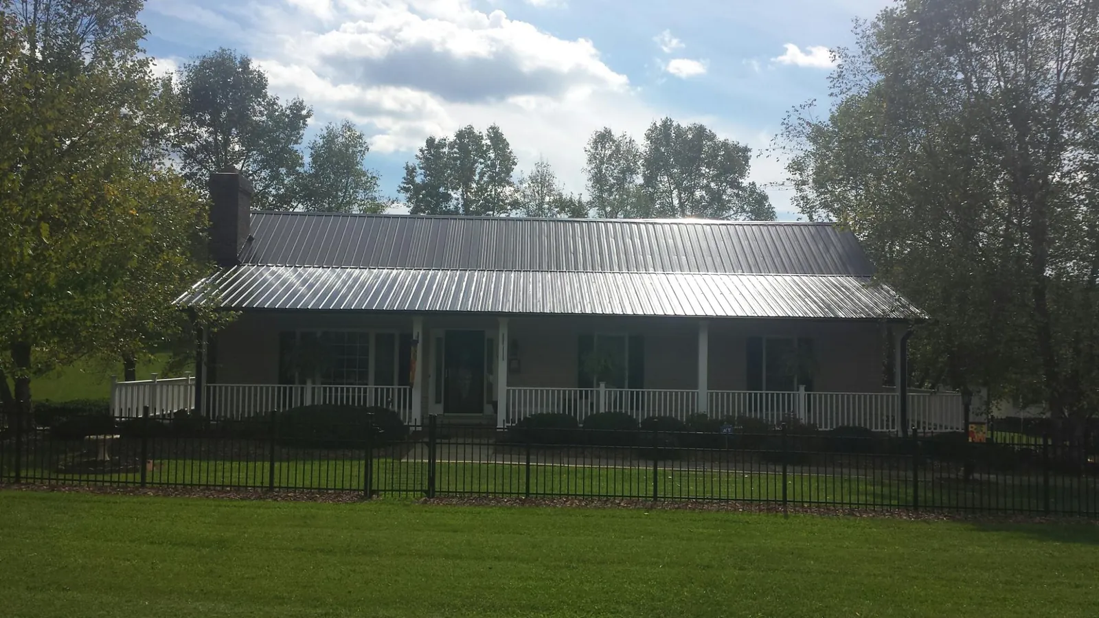 Gray metal roof on a brick ranch with a full width front porch — Gutter Guard Installation work by our crew in Genoa City