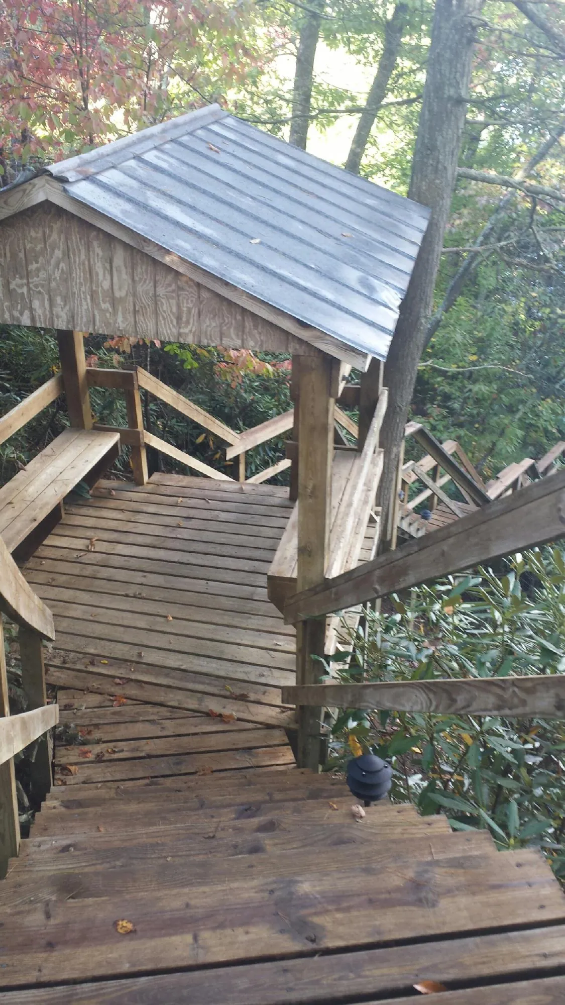 Metal roofed shelter over wooden steps on a wooded walkway — Skylight Repair & Installation work by our crew in Genoa City