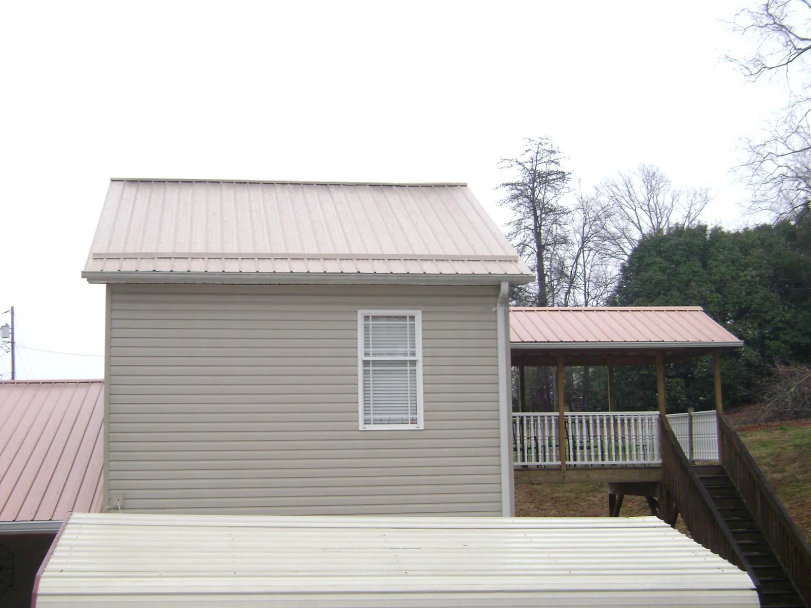 Tan metal roofs on a two story addition and attached porch, from a Roof Replacement job in Genoa City
