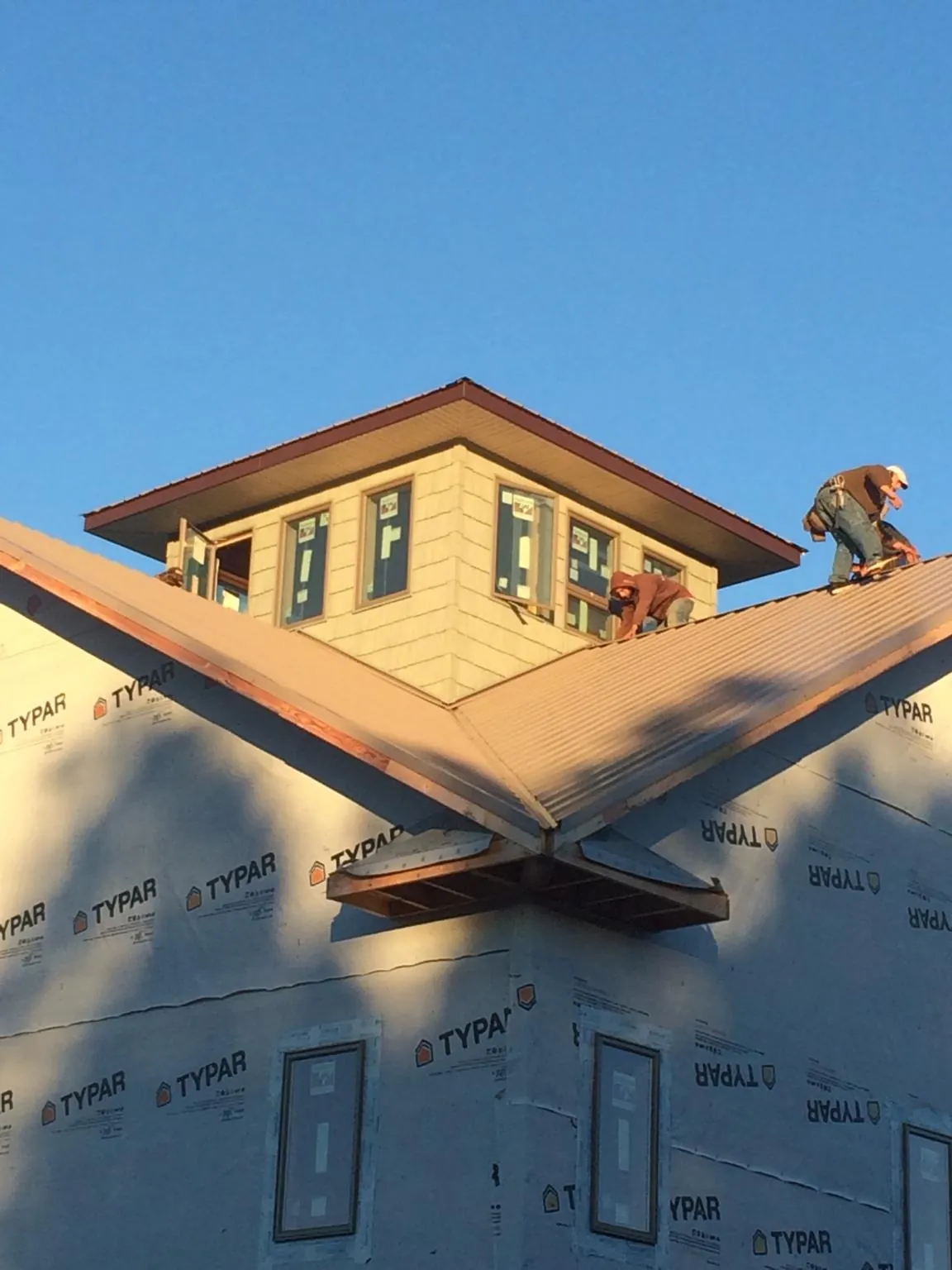 Roofers working around a rooftop cupola on a new metal roof at sunset — Roof Waterproofing in Genoa City by Roofing Brothers